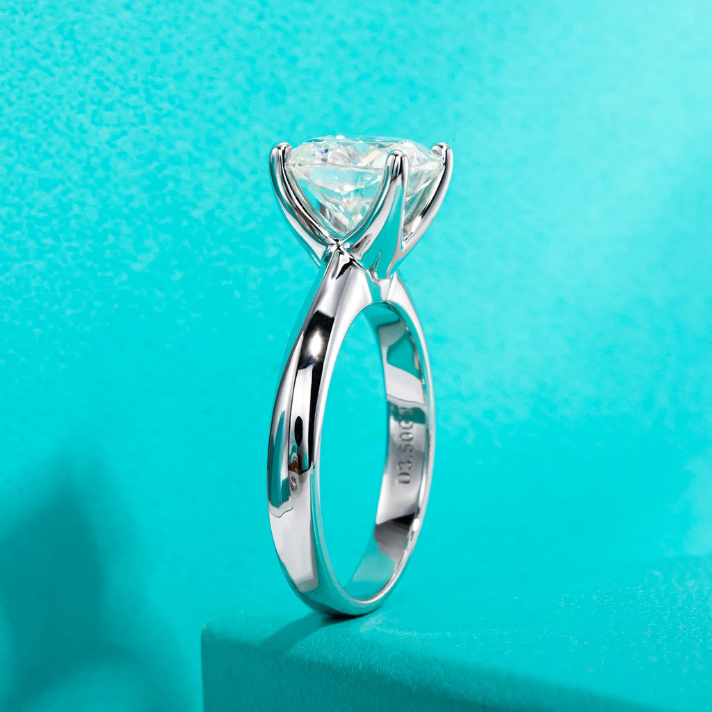 Silver ring with a large triangular gemstone on a turquoise background