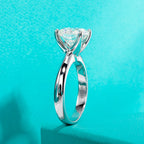 Silver ring with a large triangular gemstone on a turquoise background