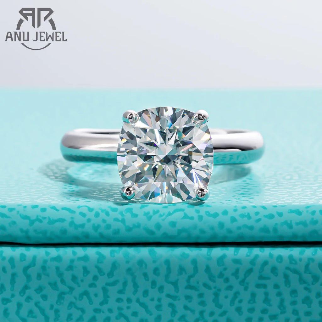 Diamond ring on a textured blue surface with 'Anu Jewel' branding.